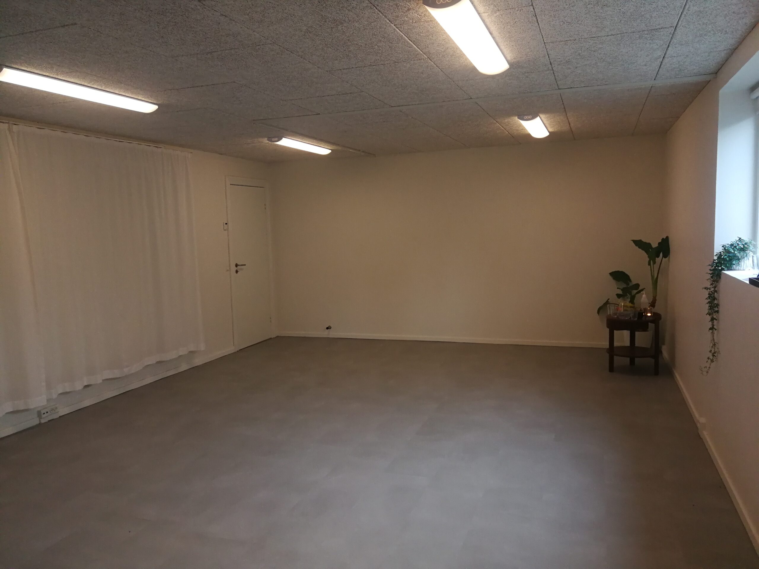 Træningssalen i Strandvejens Sundhed hvor der står et lille bord med stearinlys, vand og plante